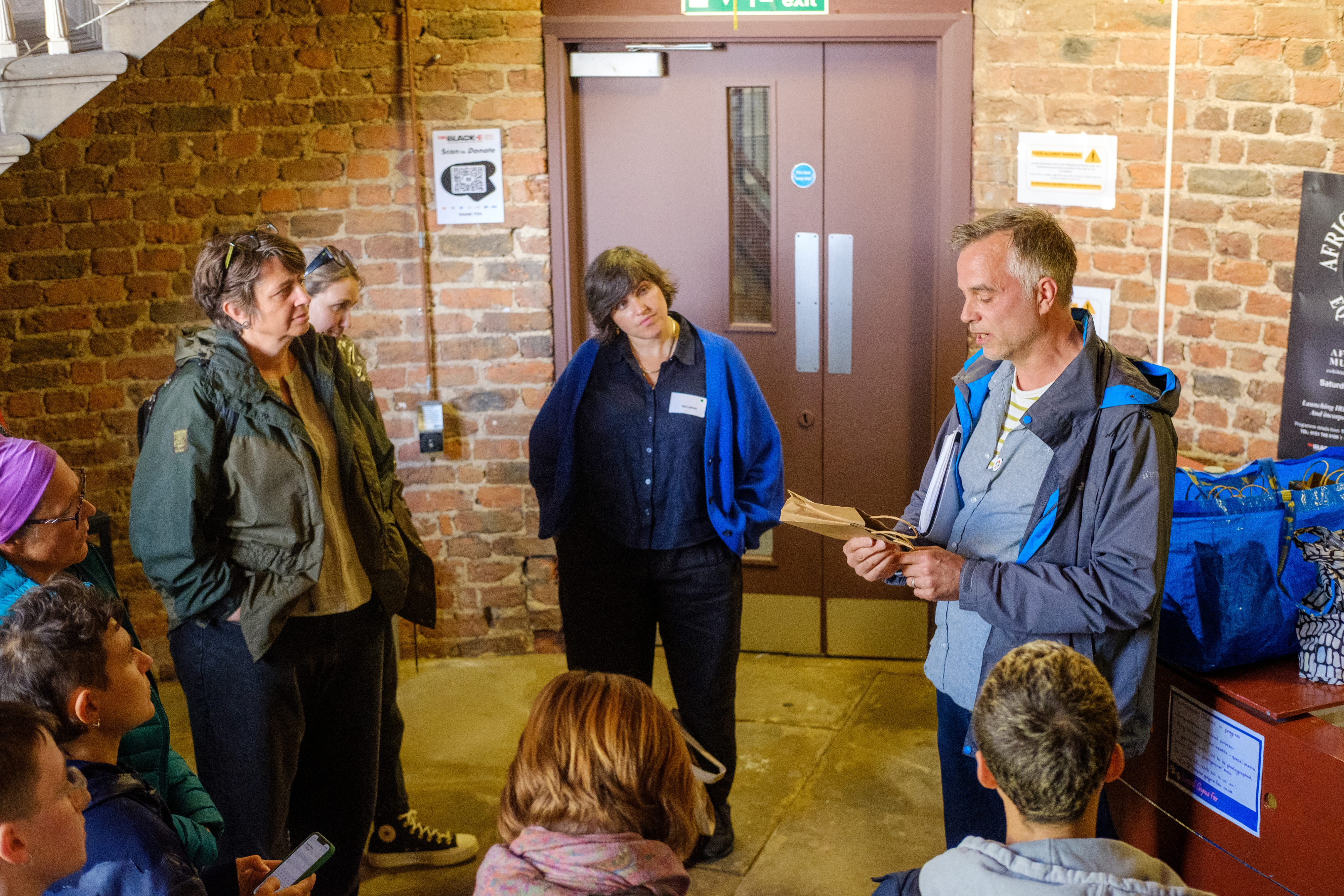 People standing in a group in a bricked room.