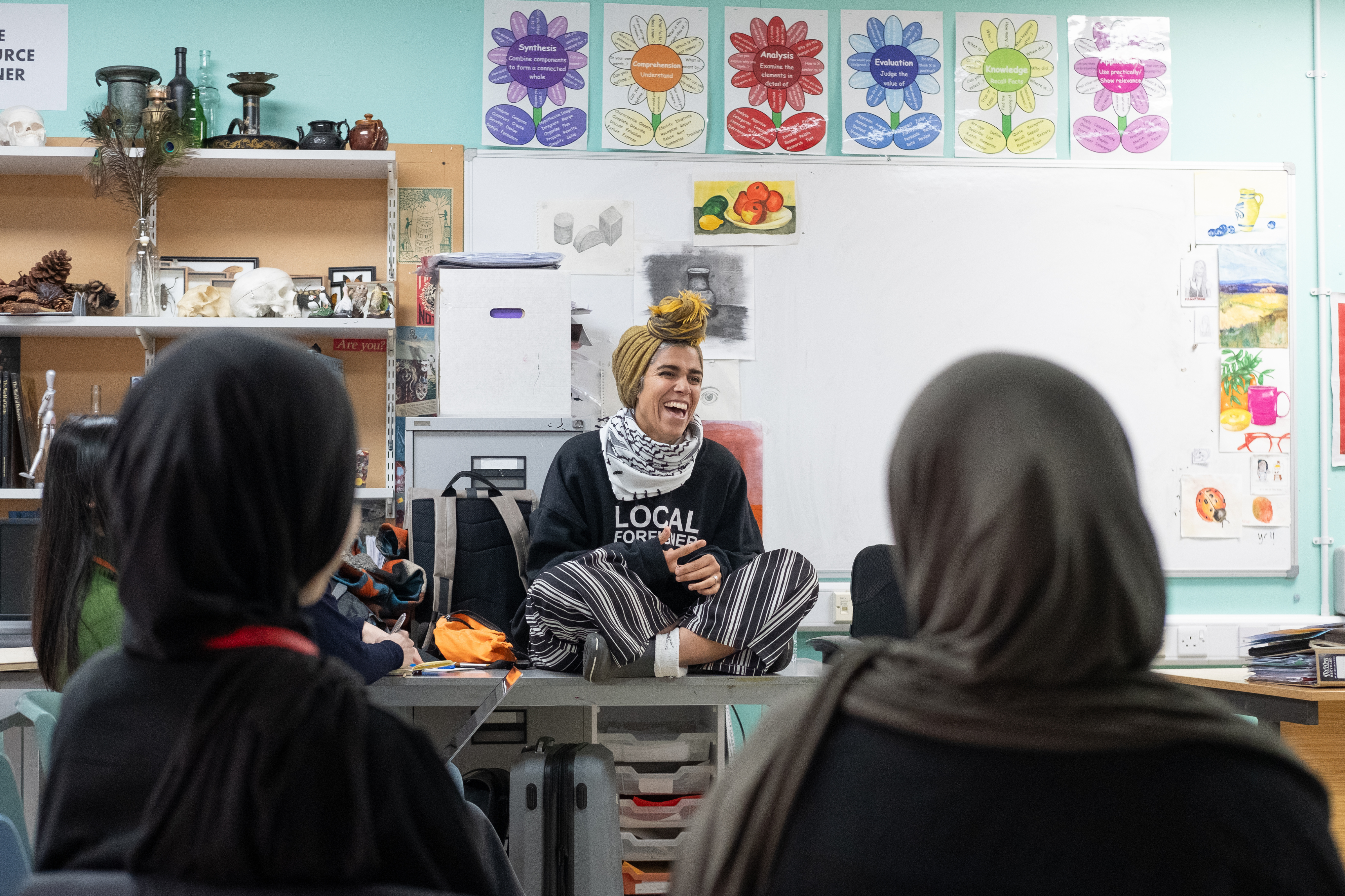 Aya Haidar sat on a table in a secondary school art classroom, laughing.