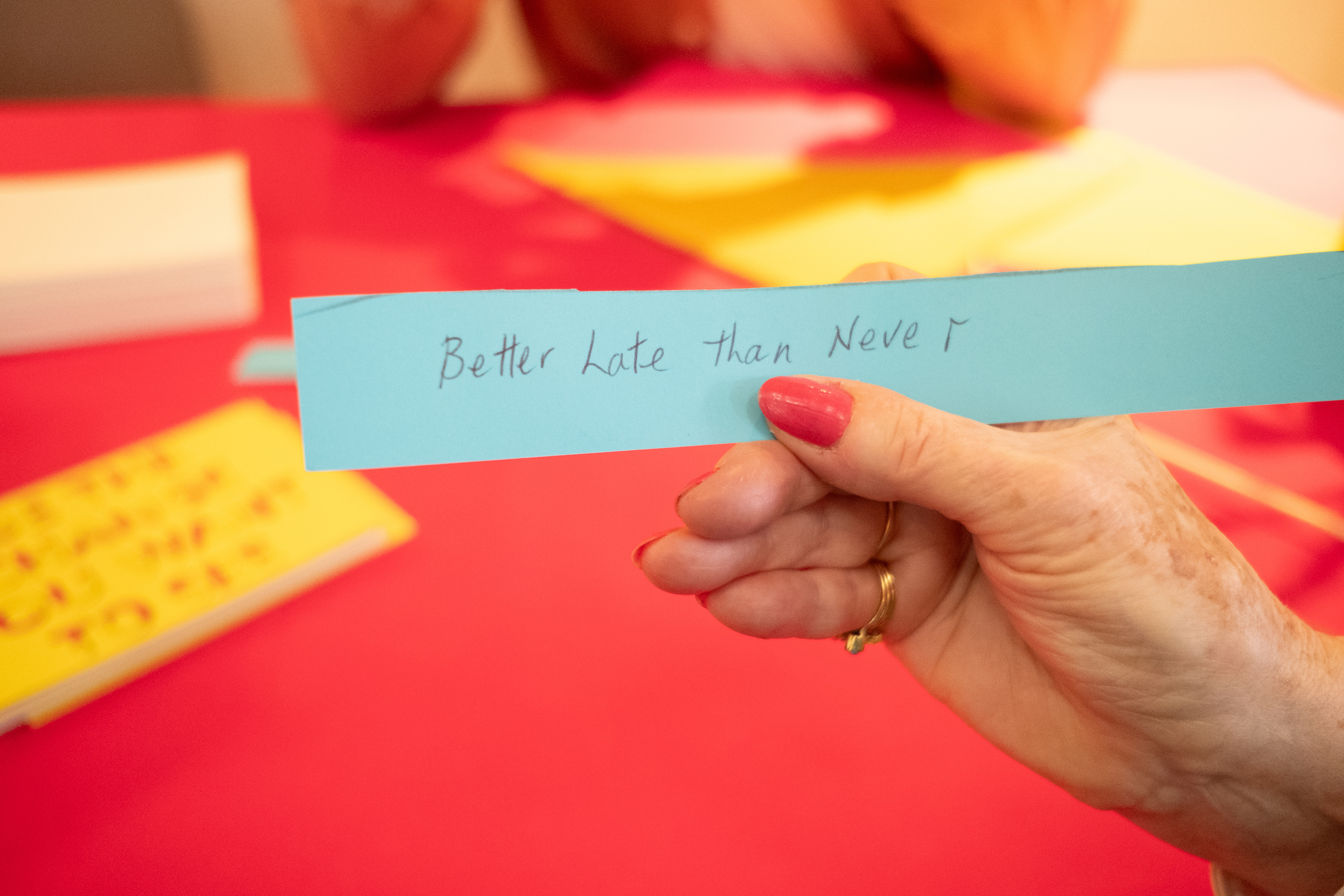 Hand holding a piece of paper which reads 'Better Late than Never'