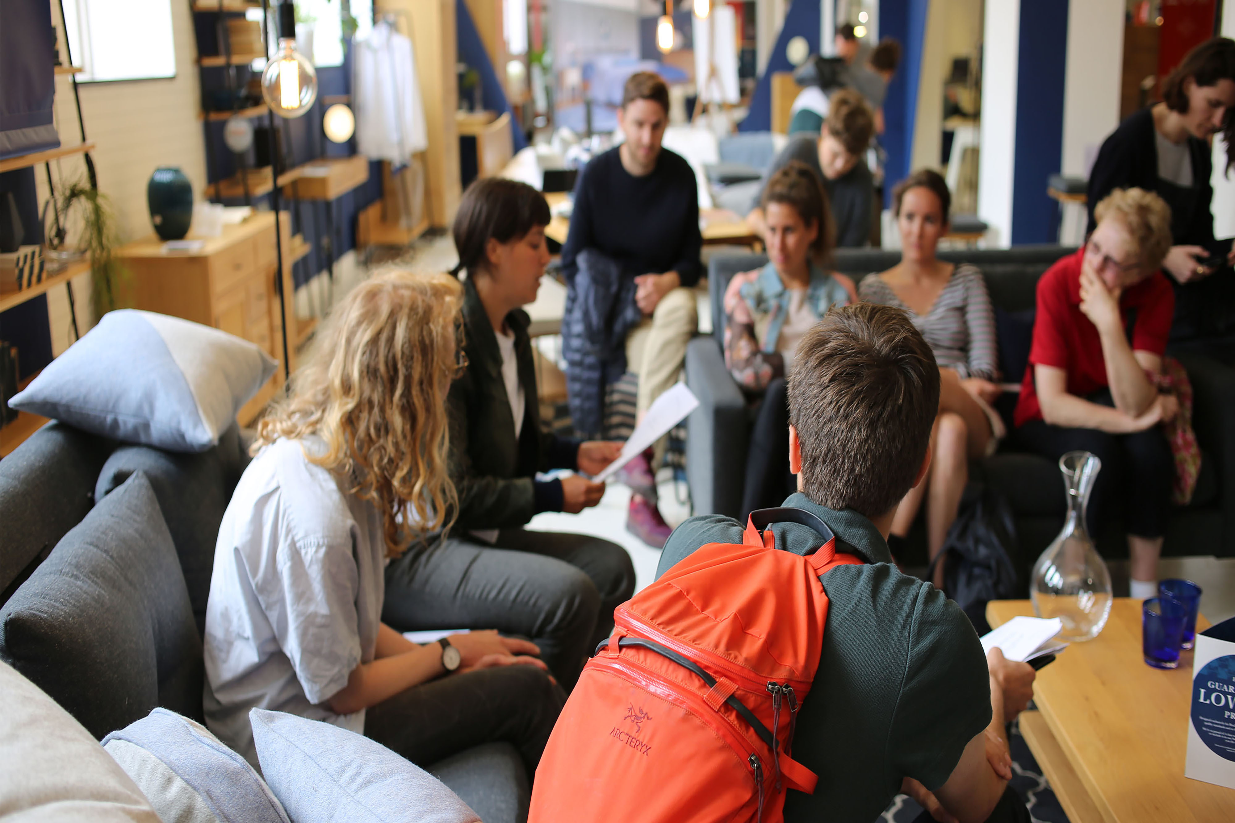 A group of people sitting in a large circle wearing backpacks inside.