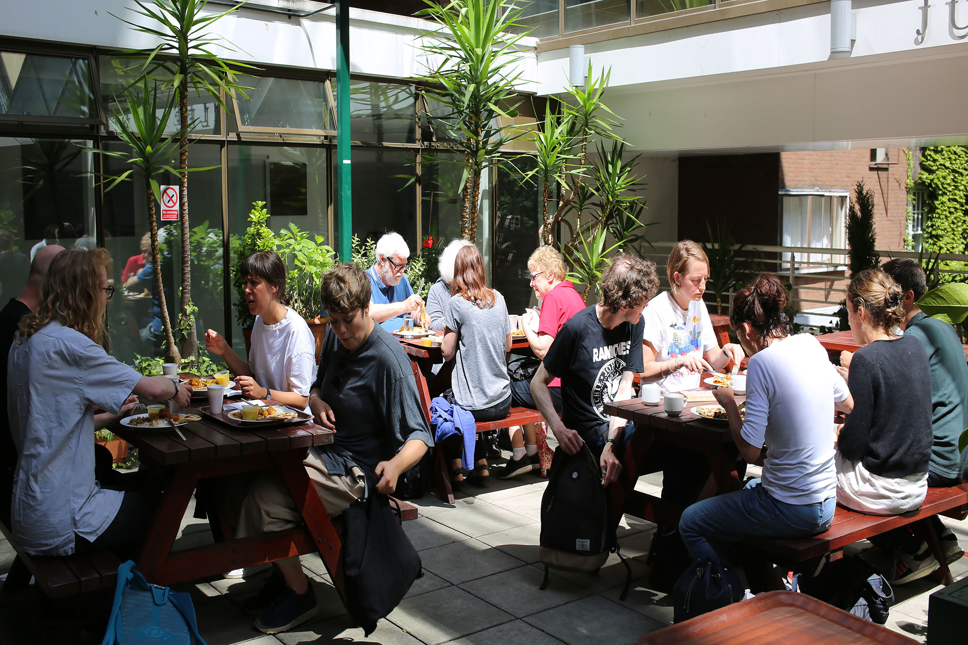 A group of people sitting in a large circle on benches outside of a pub.