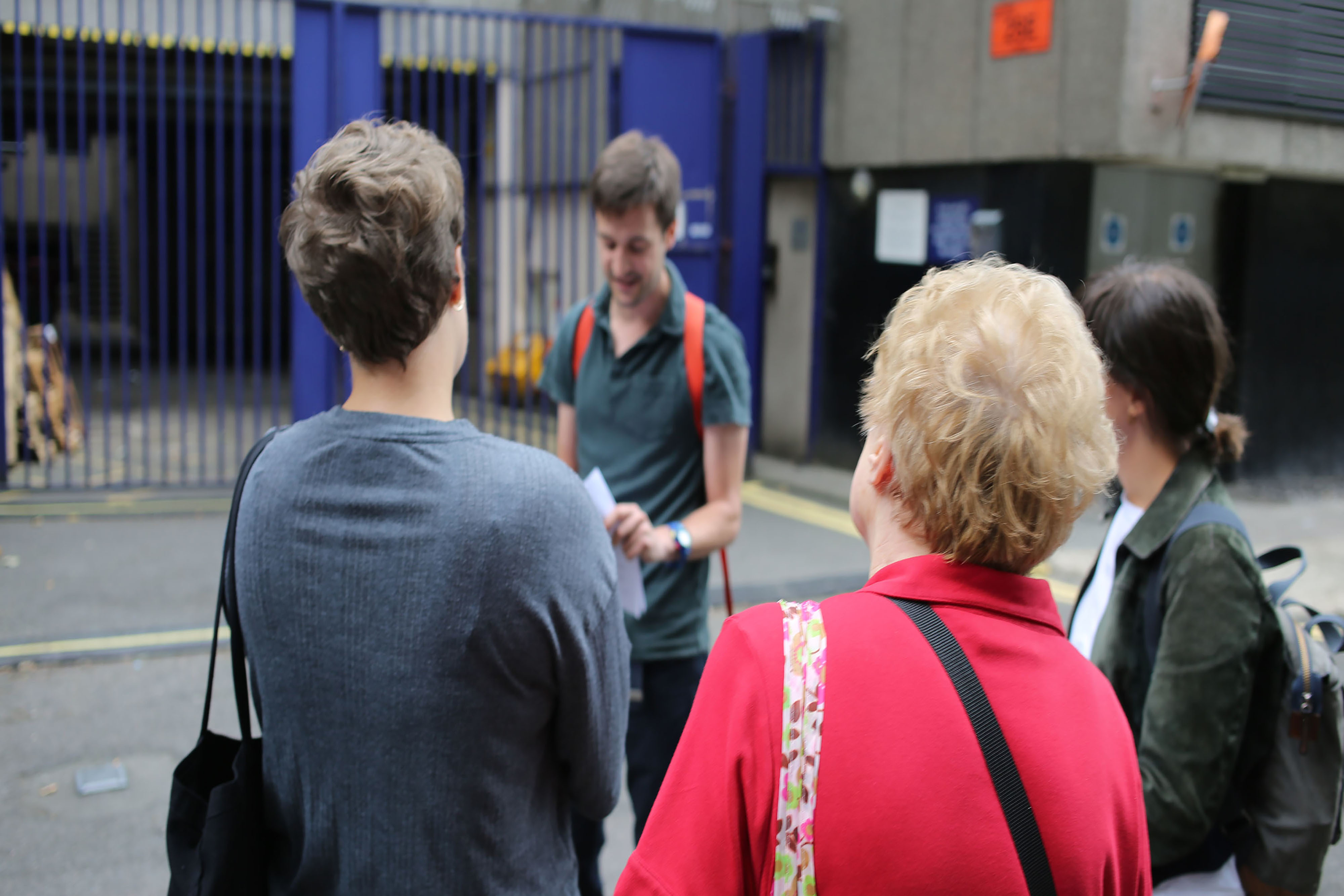 A group of people standing in a circle wearing backpacks on the street.