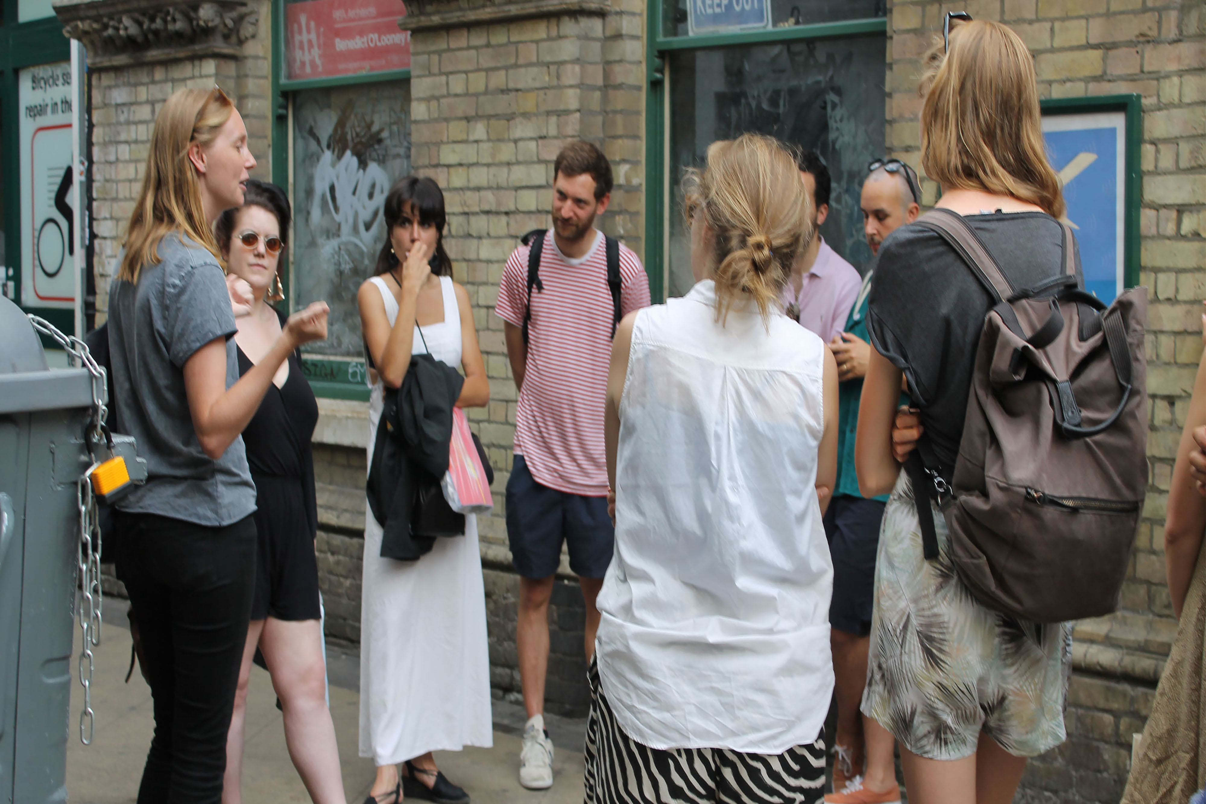 A group of people standing in a circle wearing backpacks on the street.