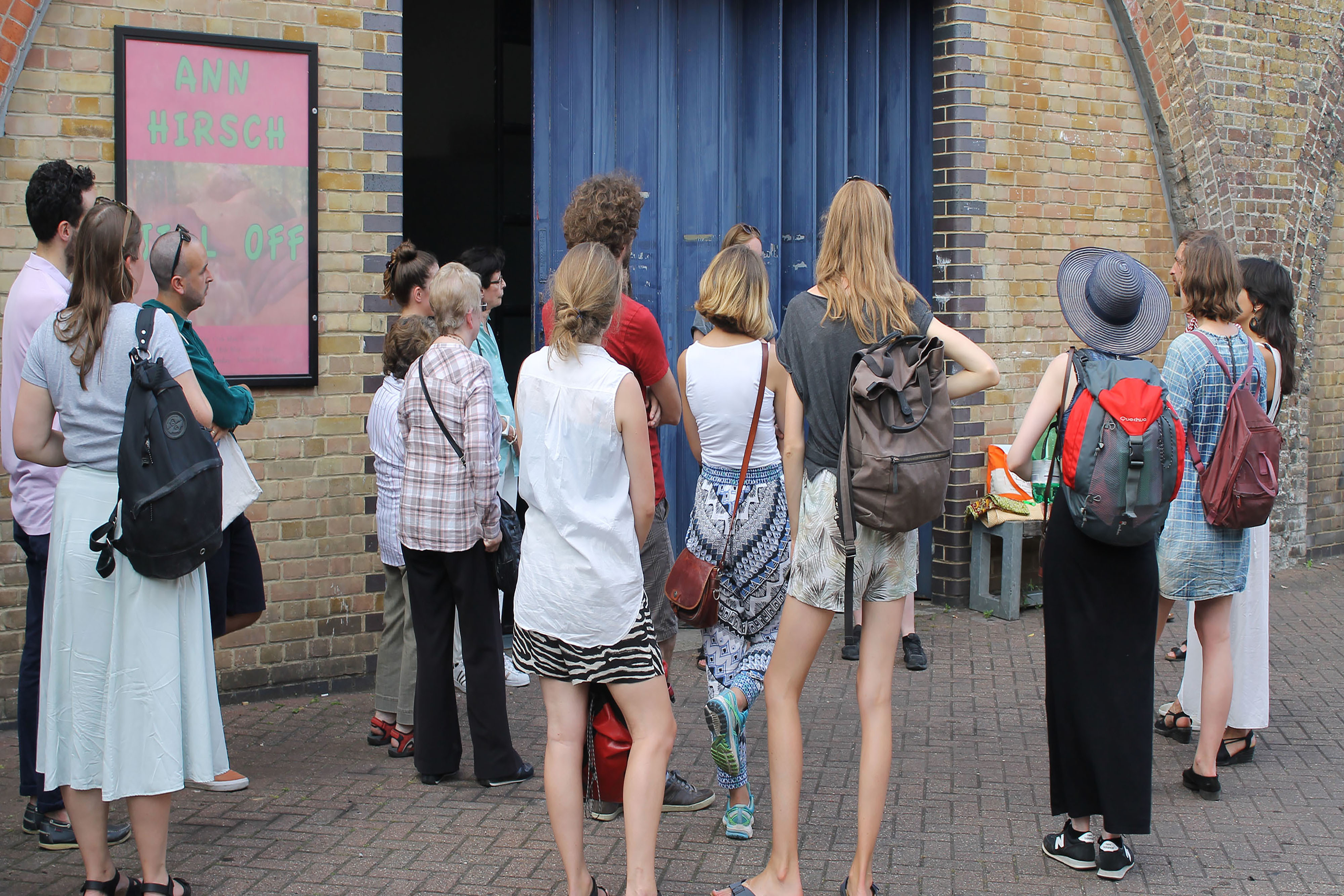 A group of people standing in a circle wearing backpacks on the street.