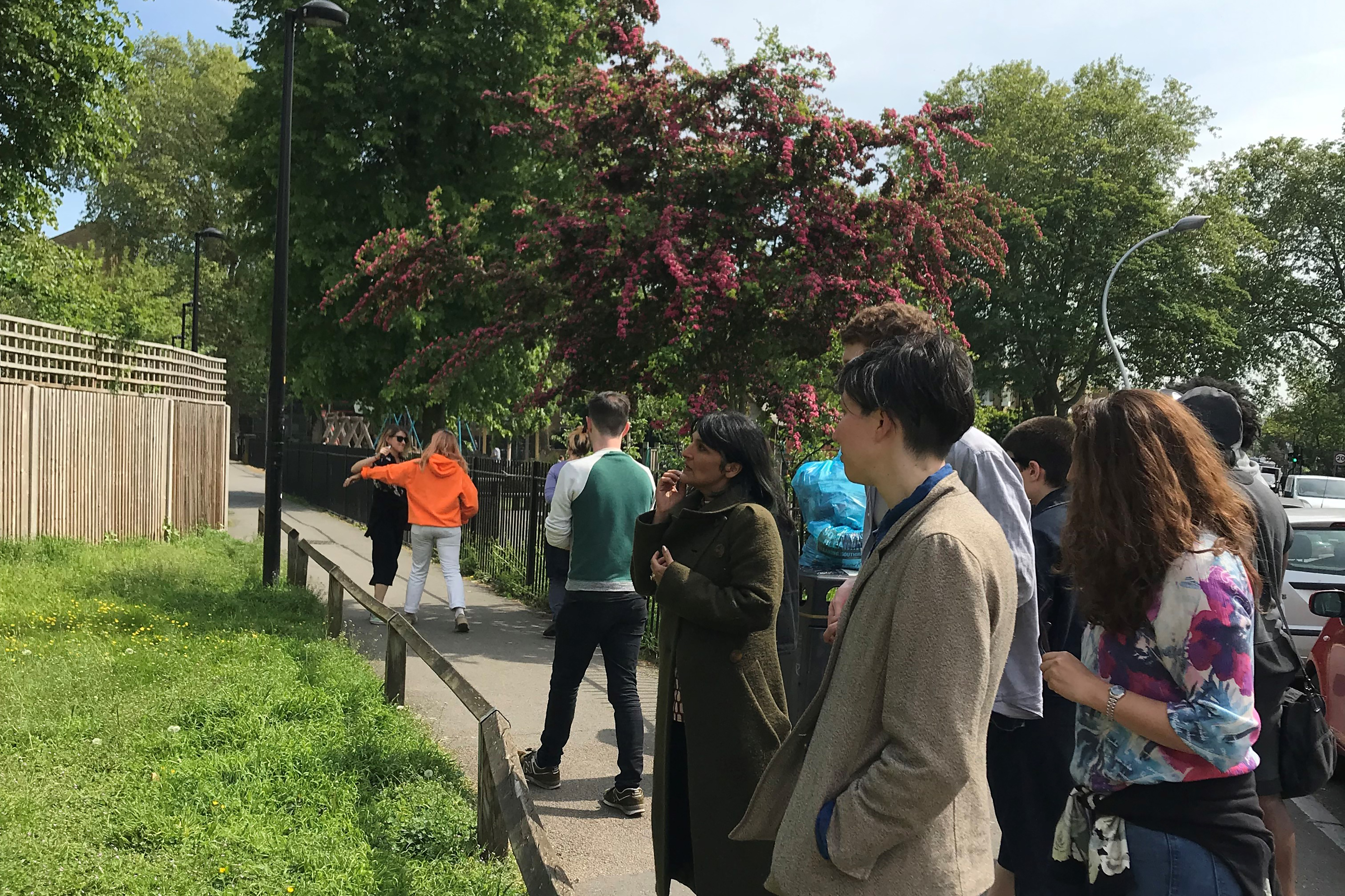 A photograph of crowd walking round a path near an outside park.