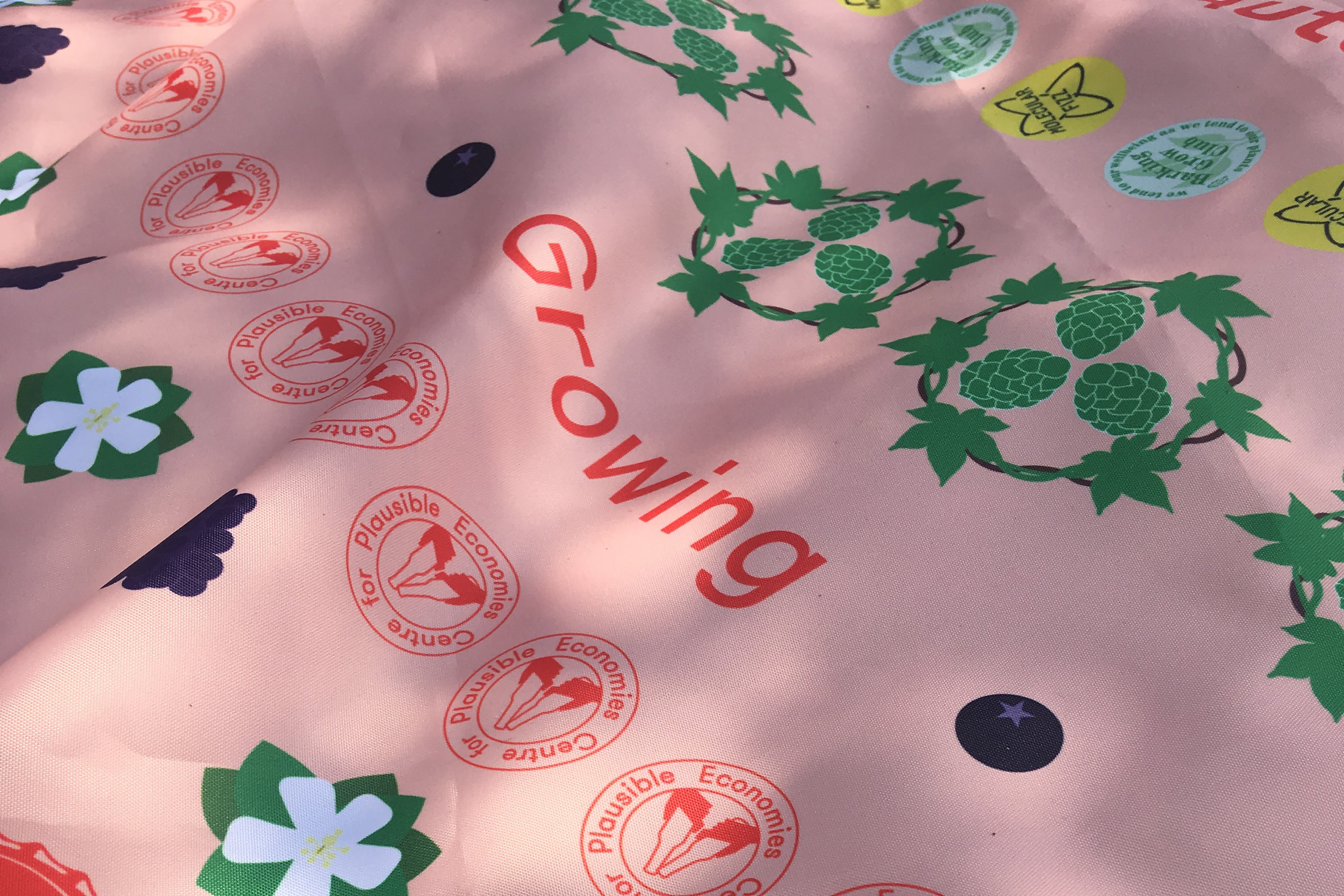 A photograph of pink sheet of cloth covered with logos and text that reads "Growing".