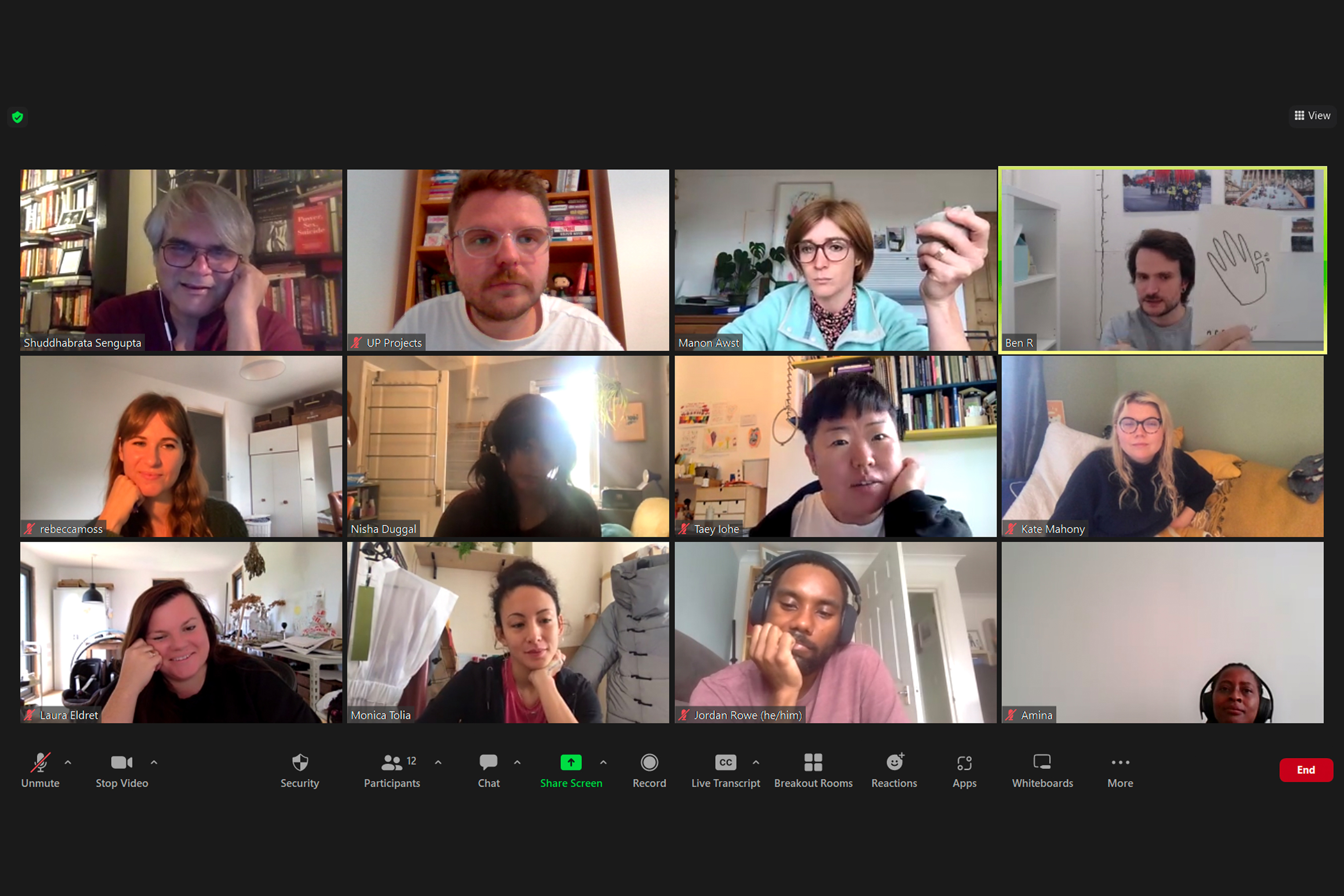 A group of people in a grid format during an online Zoom meeting with two people holding up objects in their hands while the others watch
