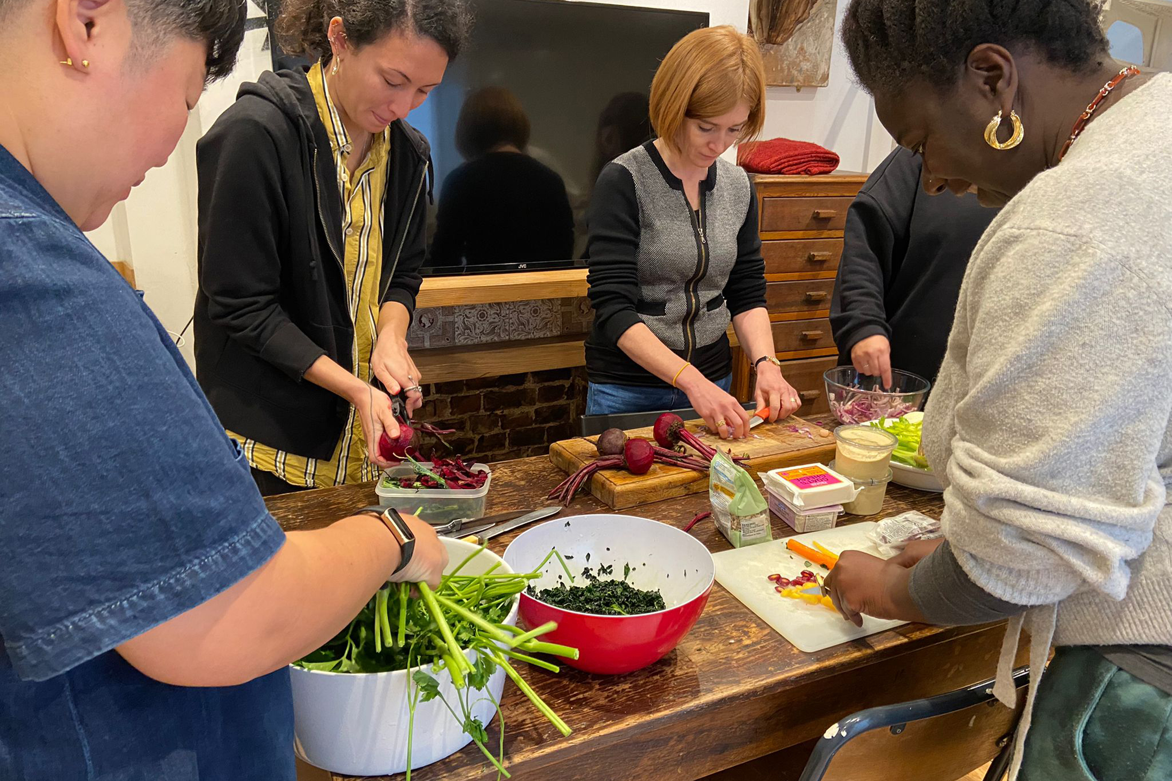 A group of people standing around a large wooden table with food on it
