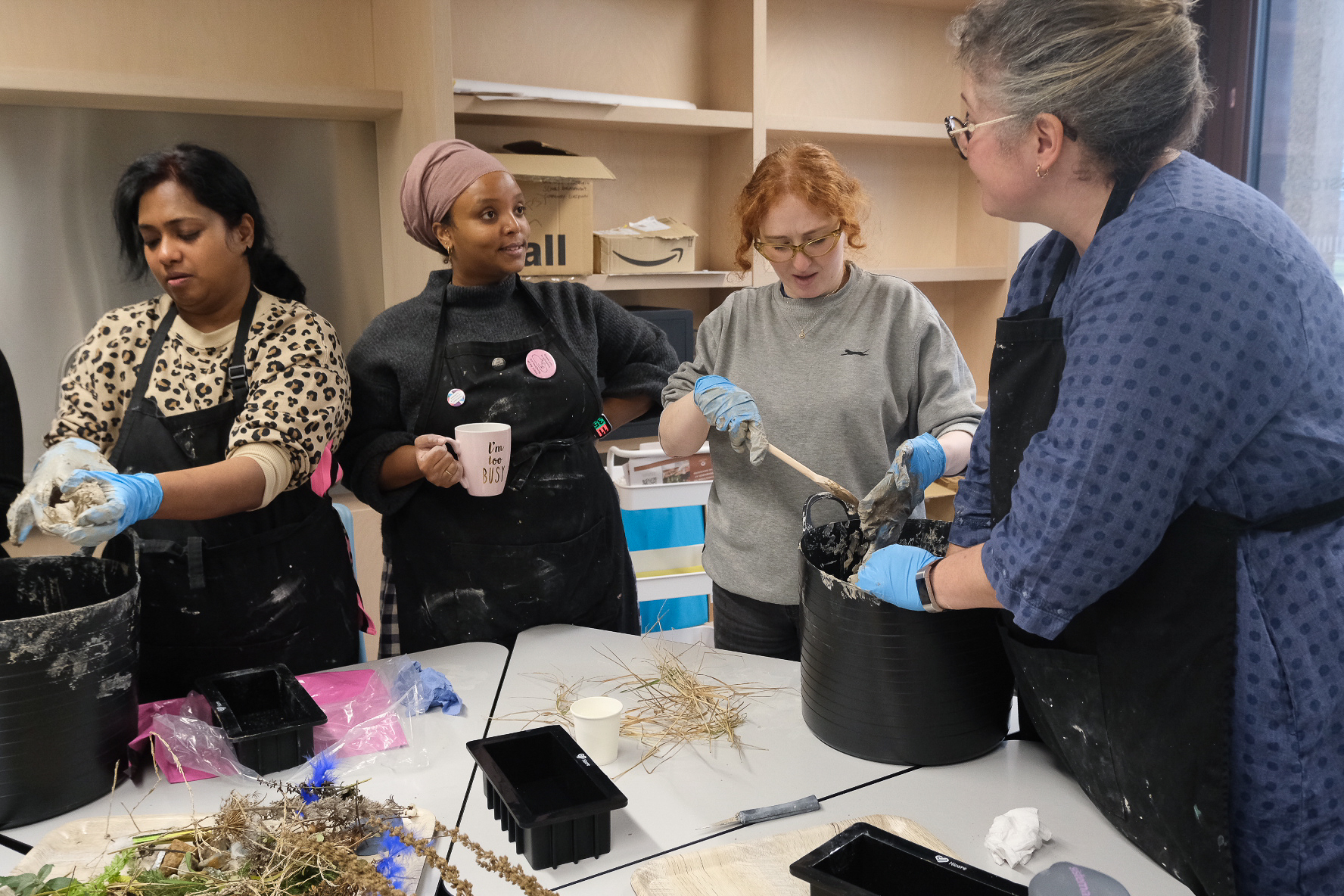 Four women making clay bricks around a table.