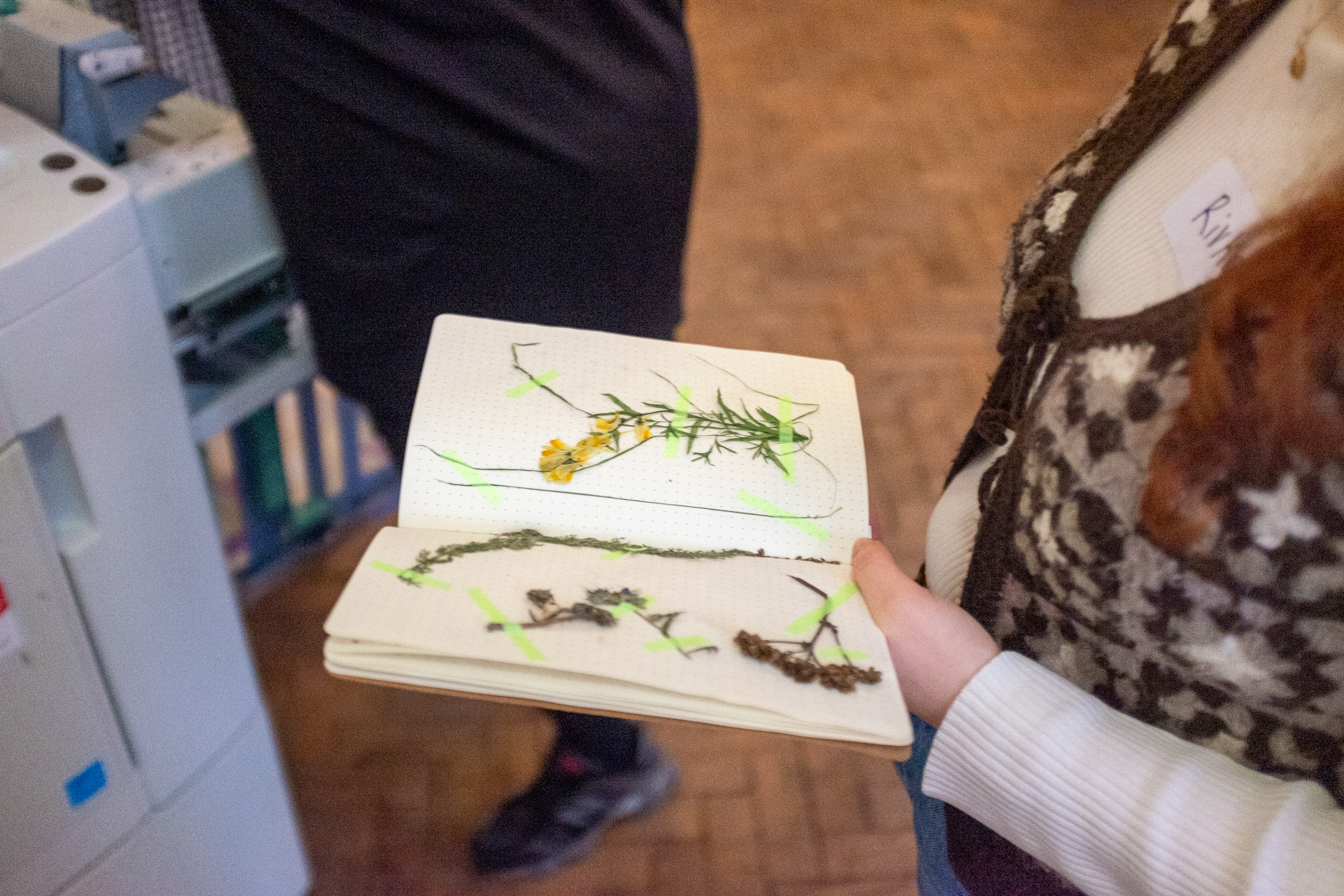 Close up of a notebook with flowers taped down to it being held by a woman.