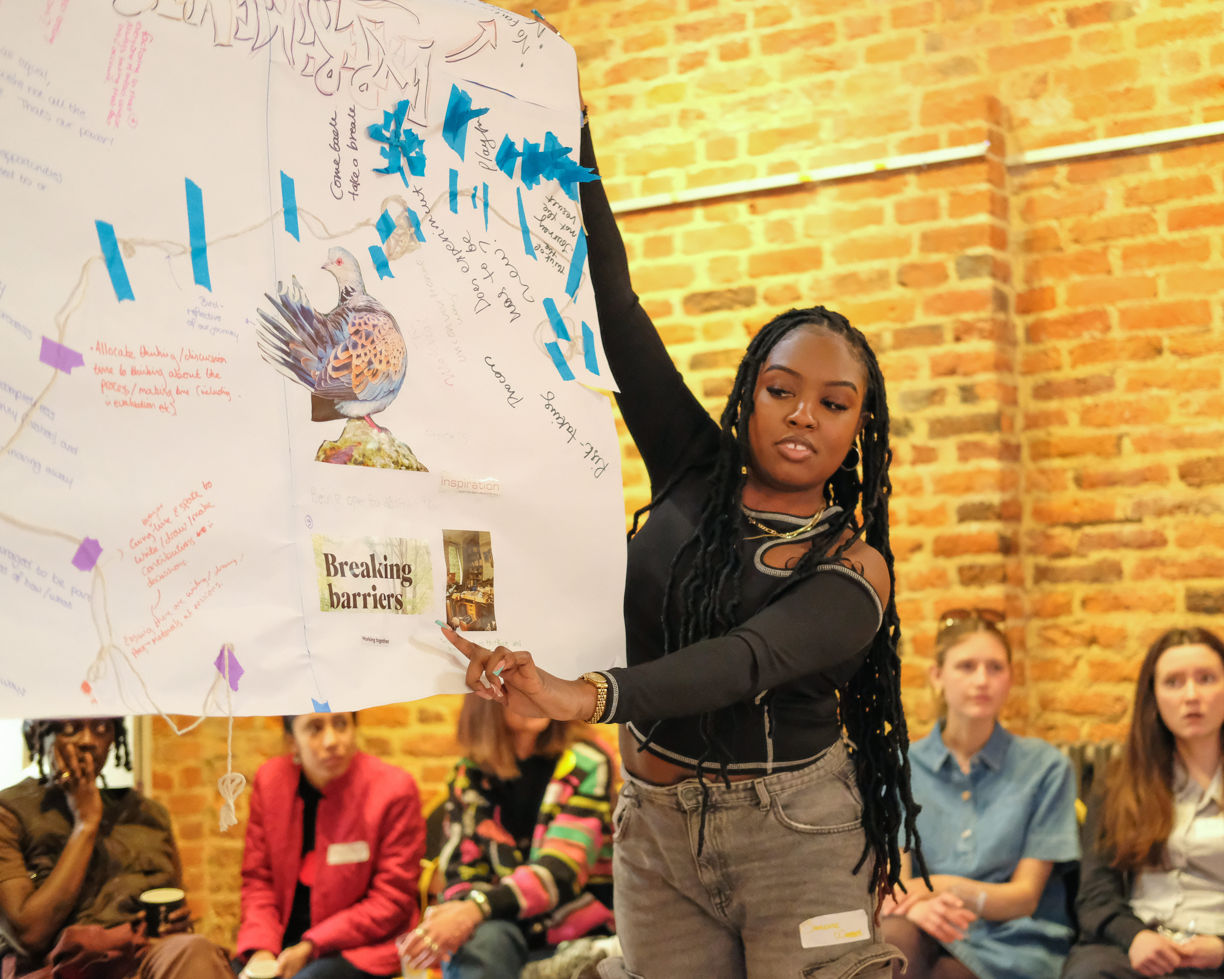 A person holds up a piece of paper on which reads 'Breaking Barriers'