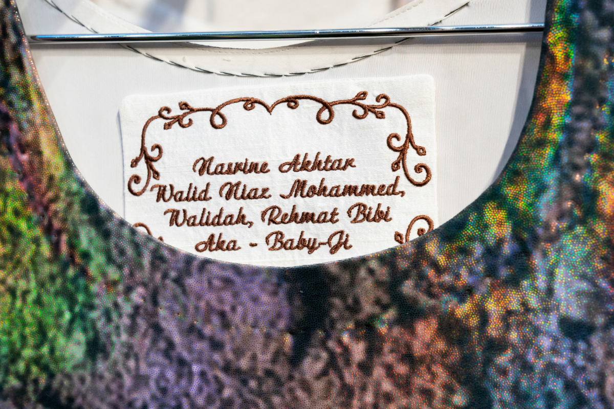 A close-up of a printed kamees with detail on the inside collar with names stitched into the fabric in an italic handwritten style.