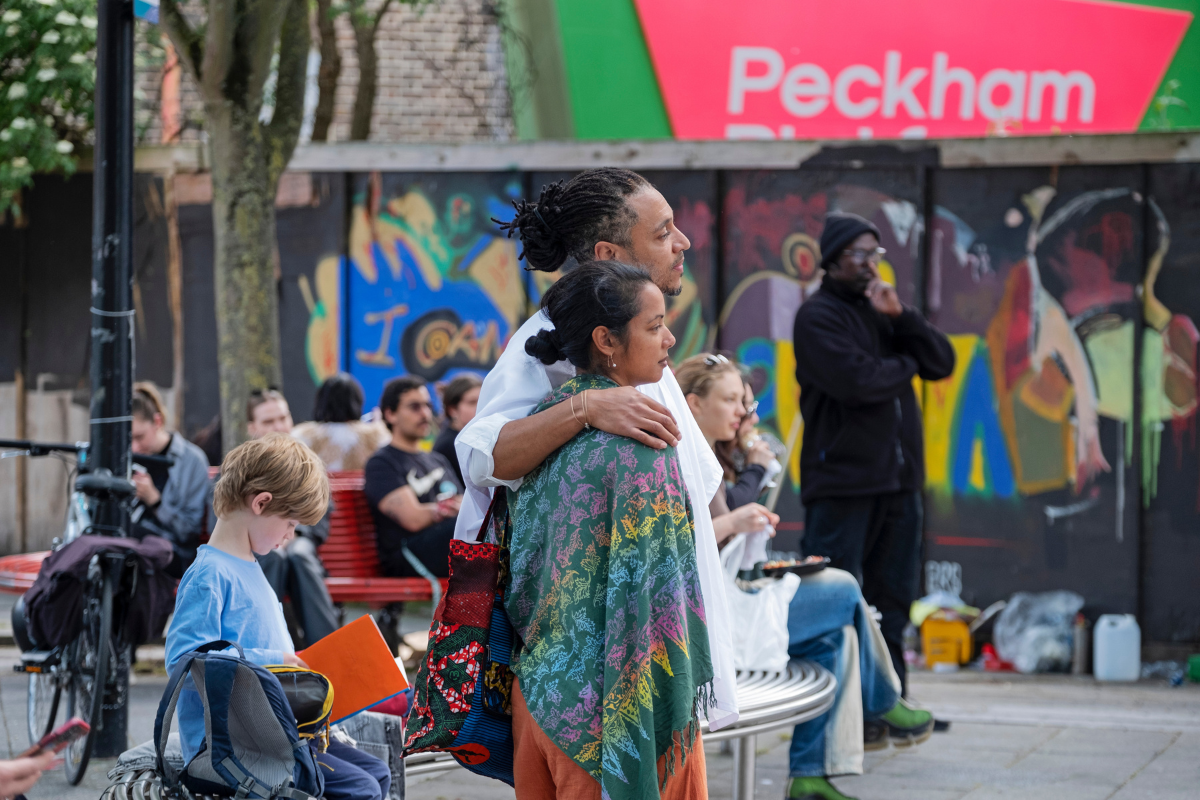 A group of audience members watching a performance on a street.