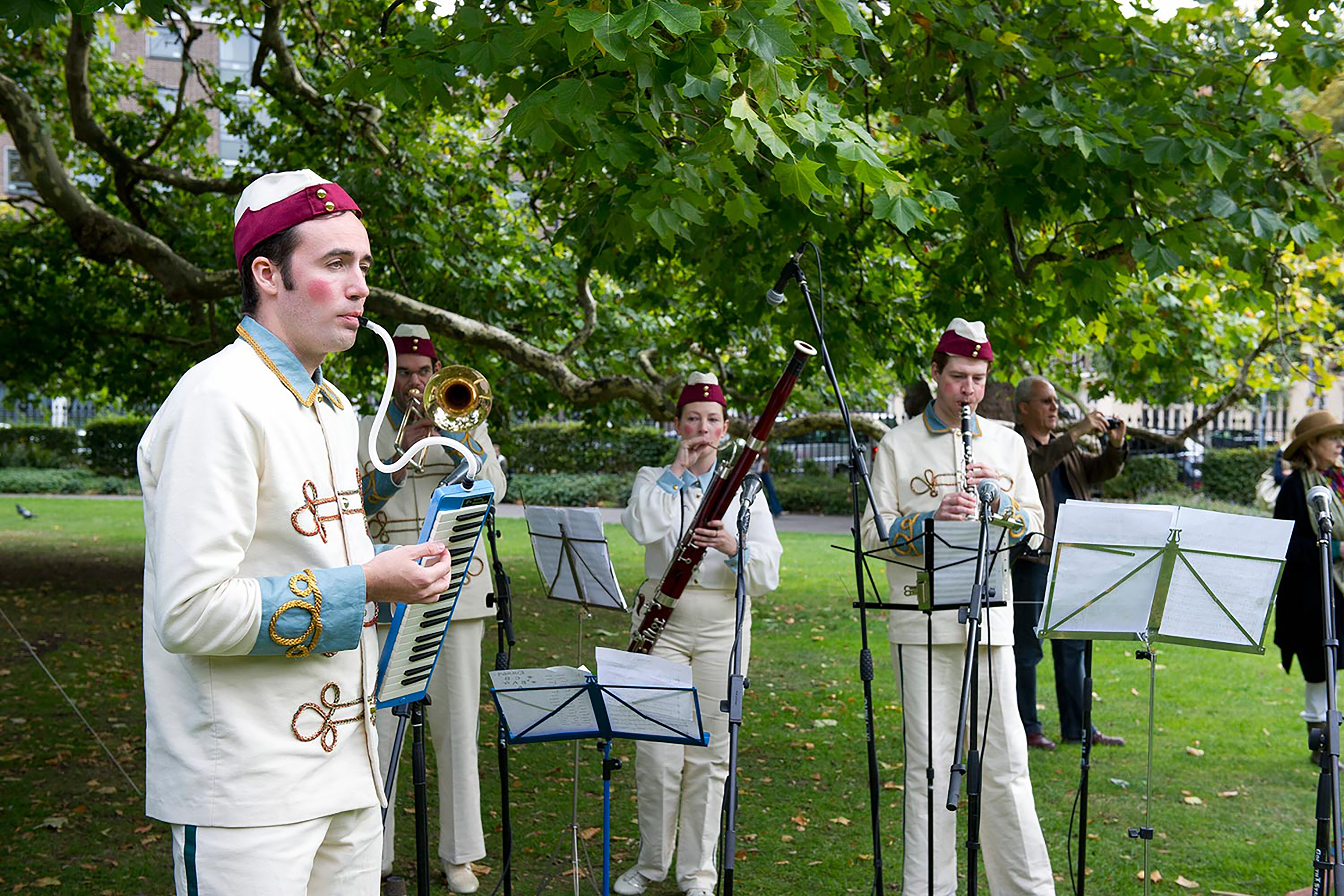 A photograph of a quartet playing instruments in the park.