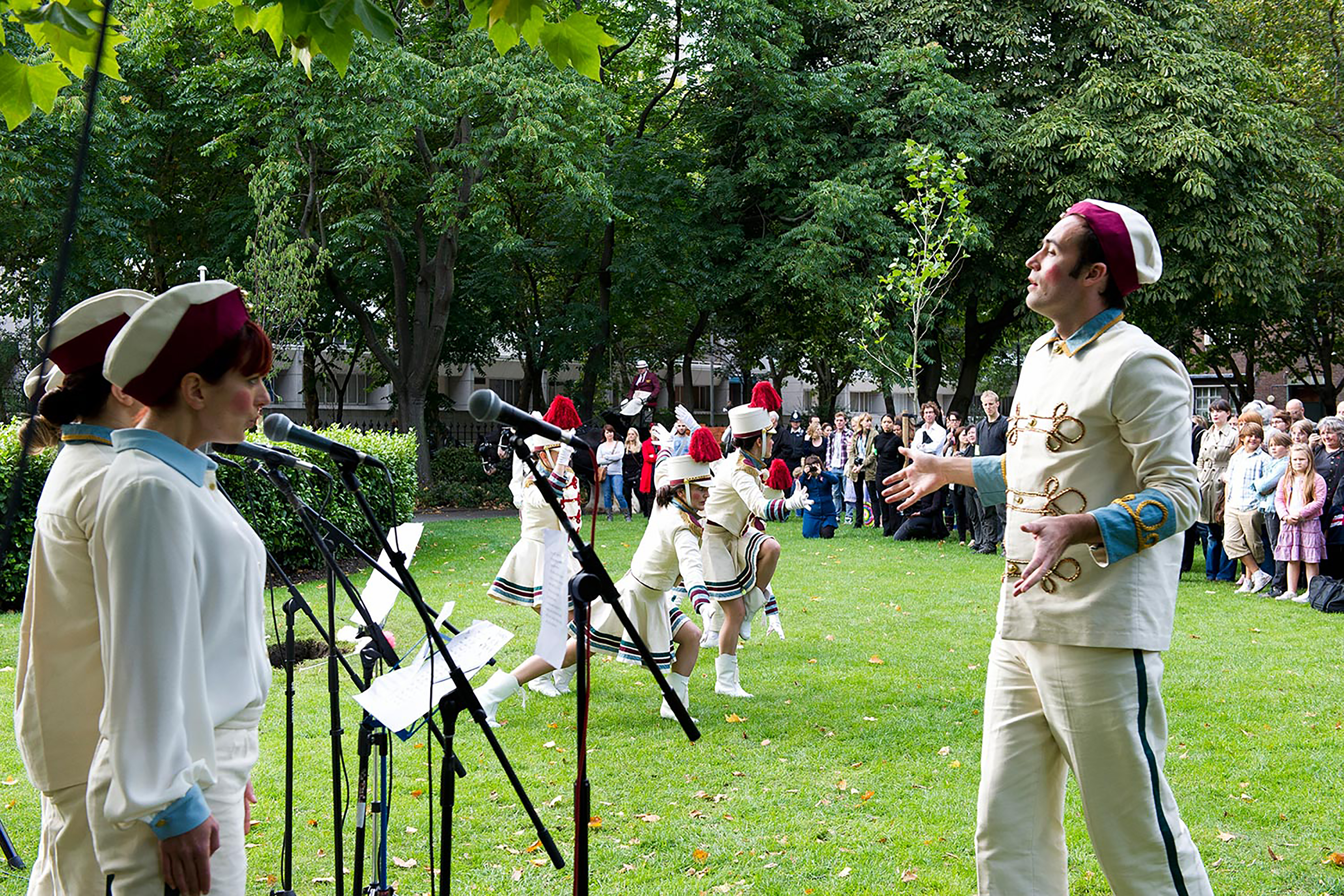A photograph of performers singing and dancing in front of a crowd. 