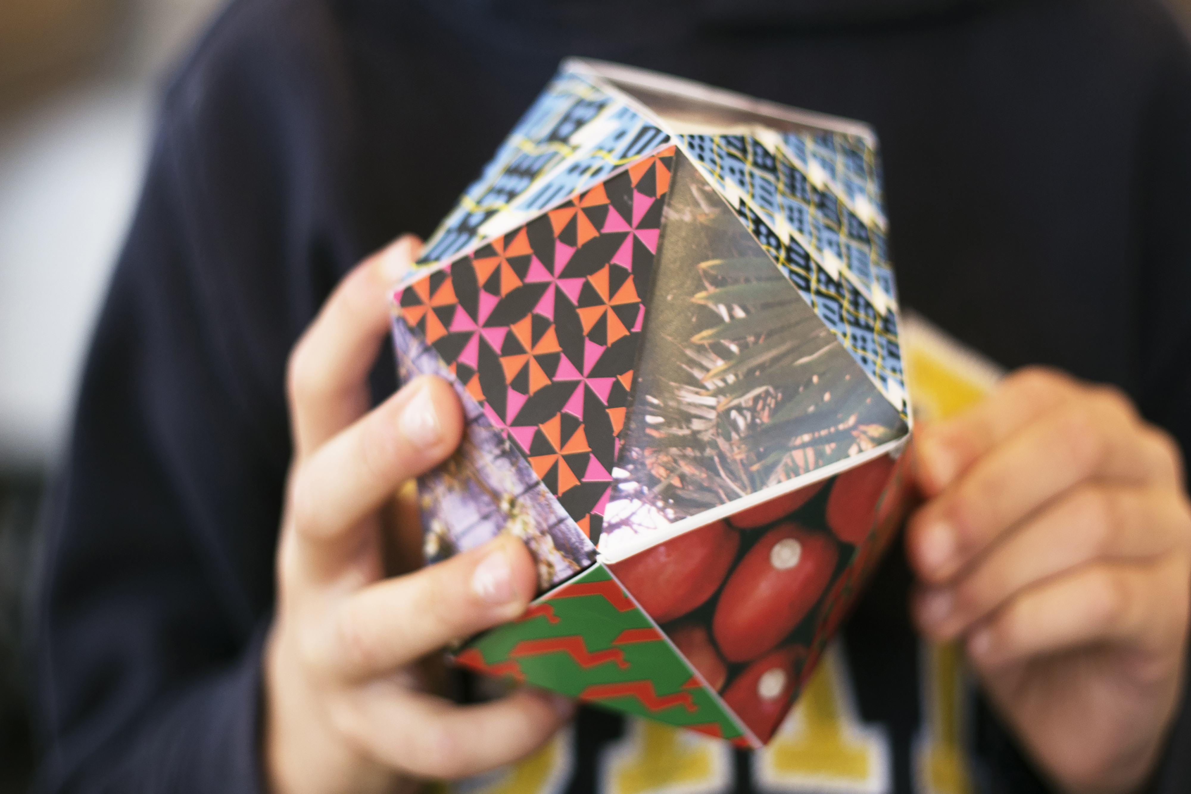 A person playing a large geometric hand-made shape made up of geometric patterns.