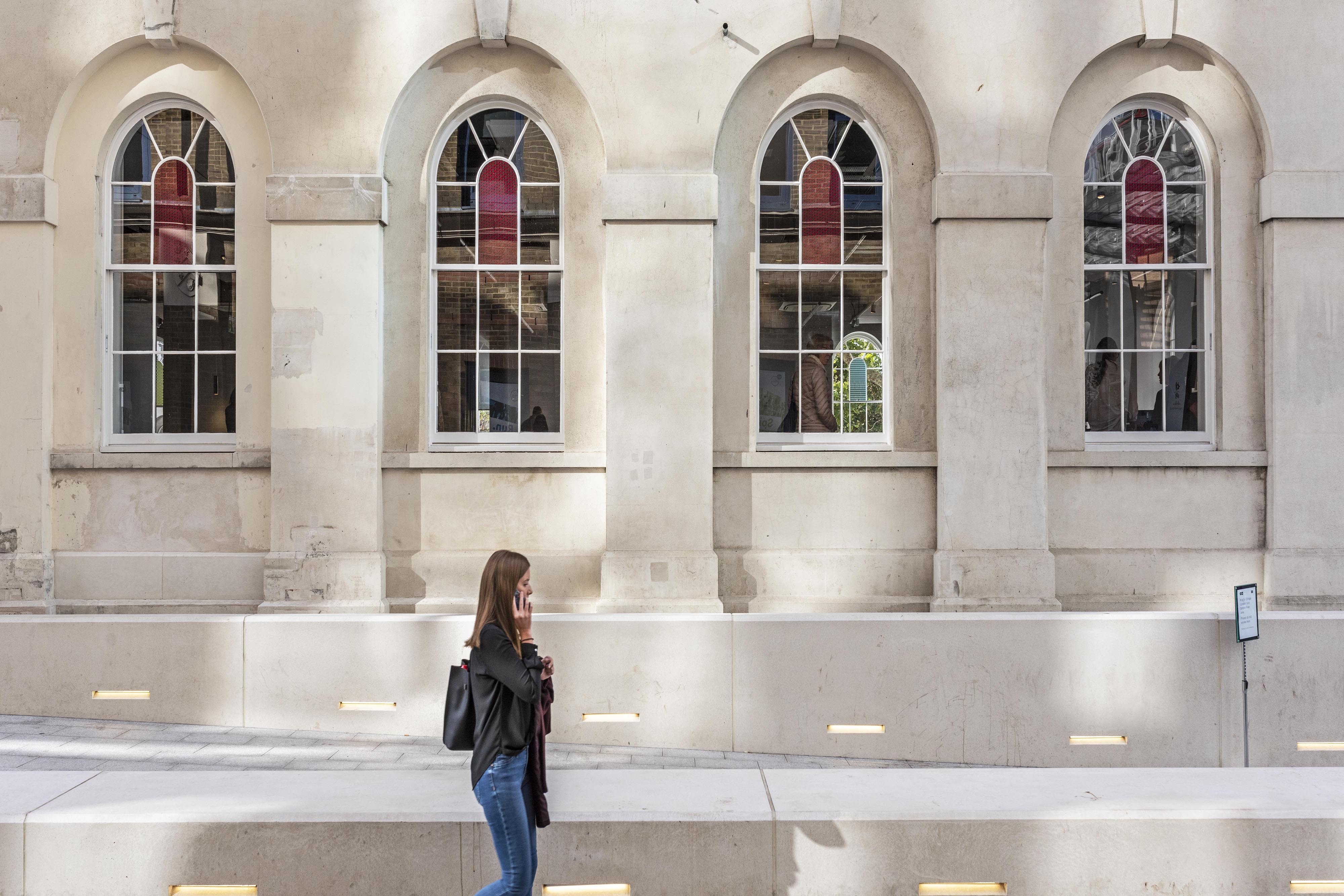 Outside of a gallery with white walls with large, coloured stain glass windows.