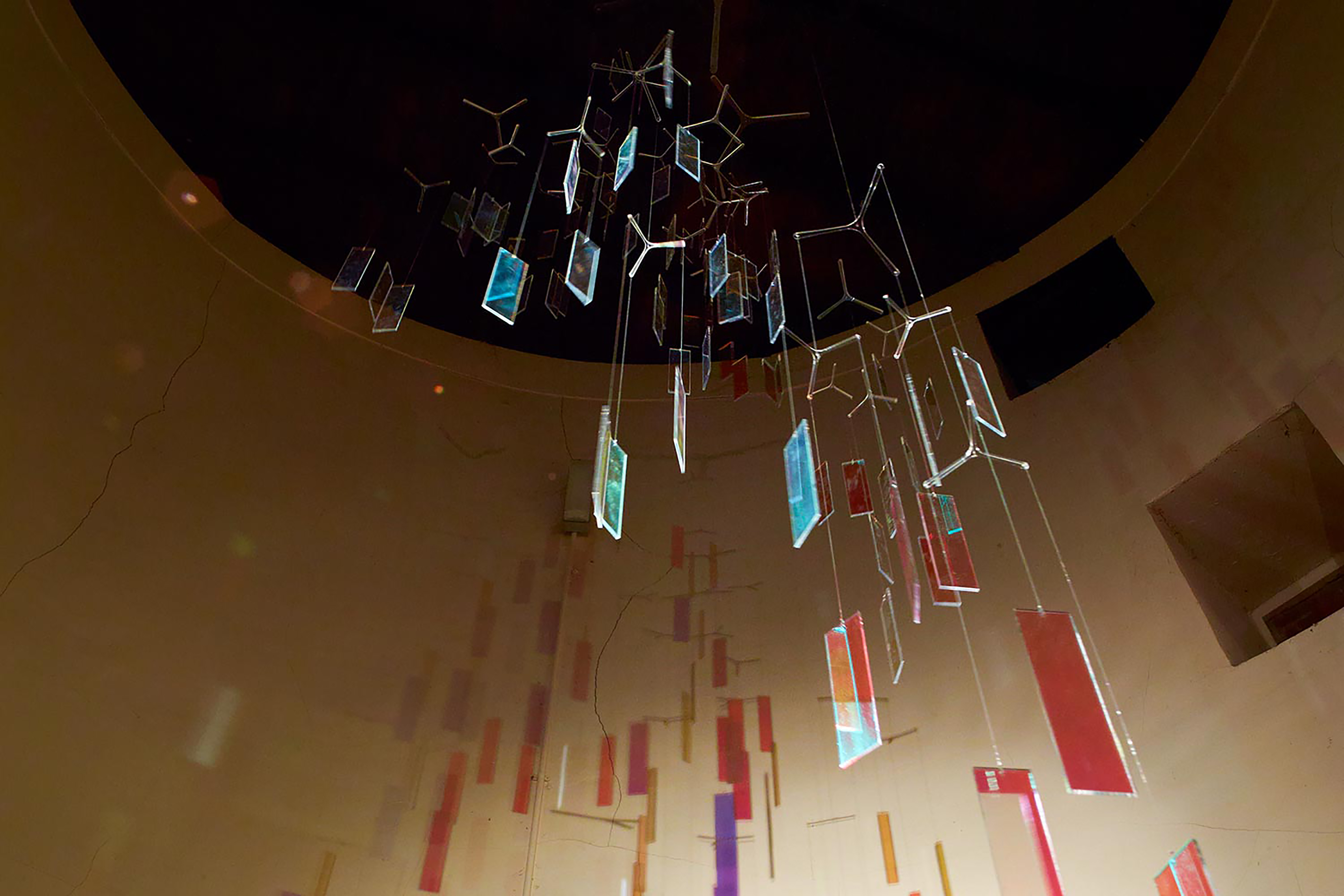 A collection of different coloured shapes hanging down from the ceiling in a formation.