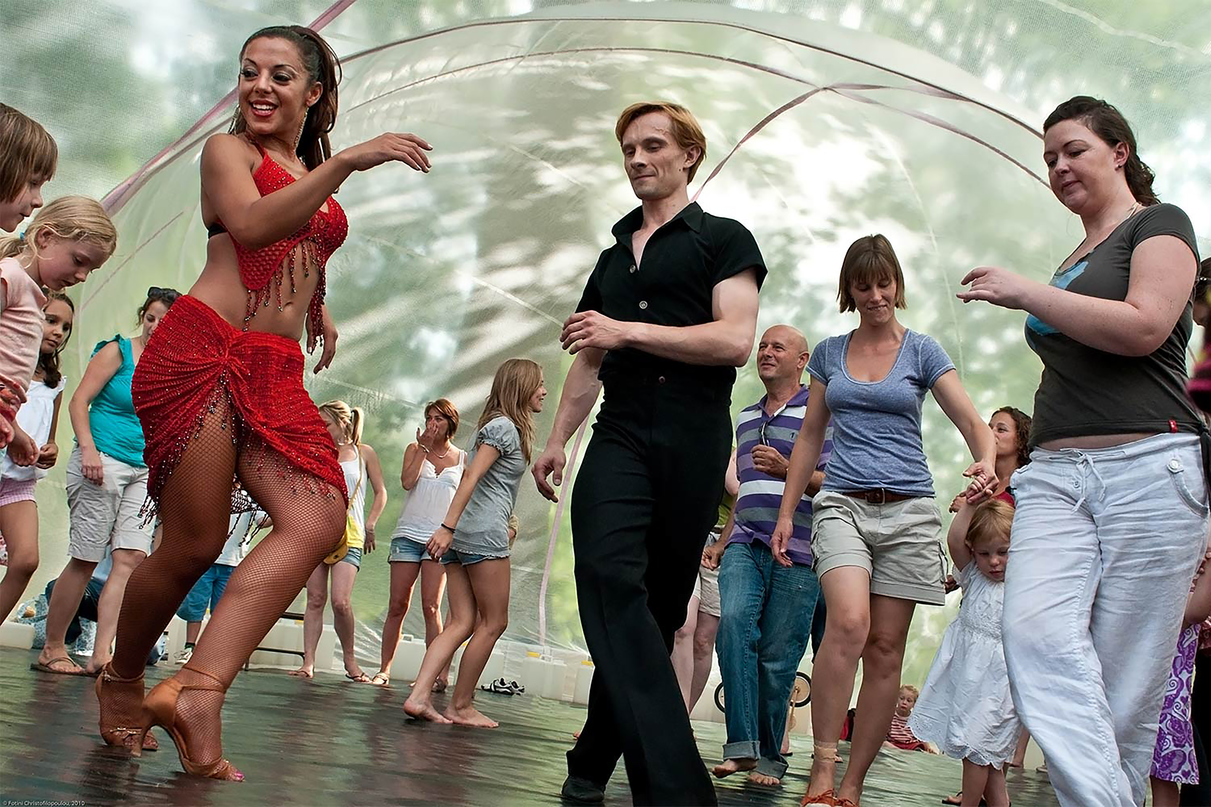 A photograph of a group of people preforming salsa dance in a transparent dome tent.