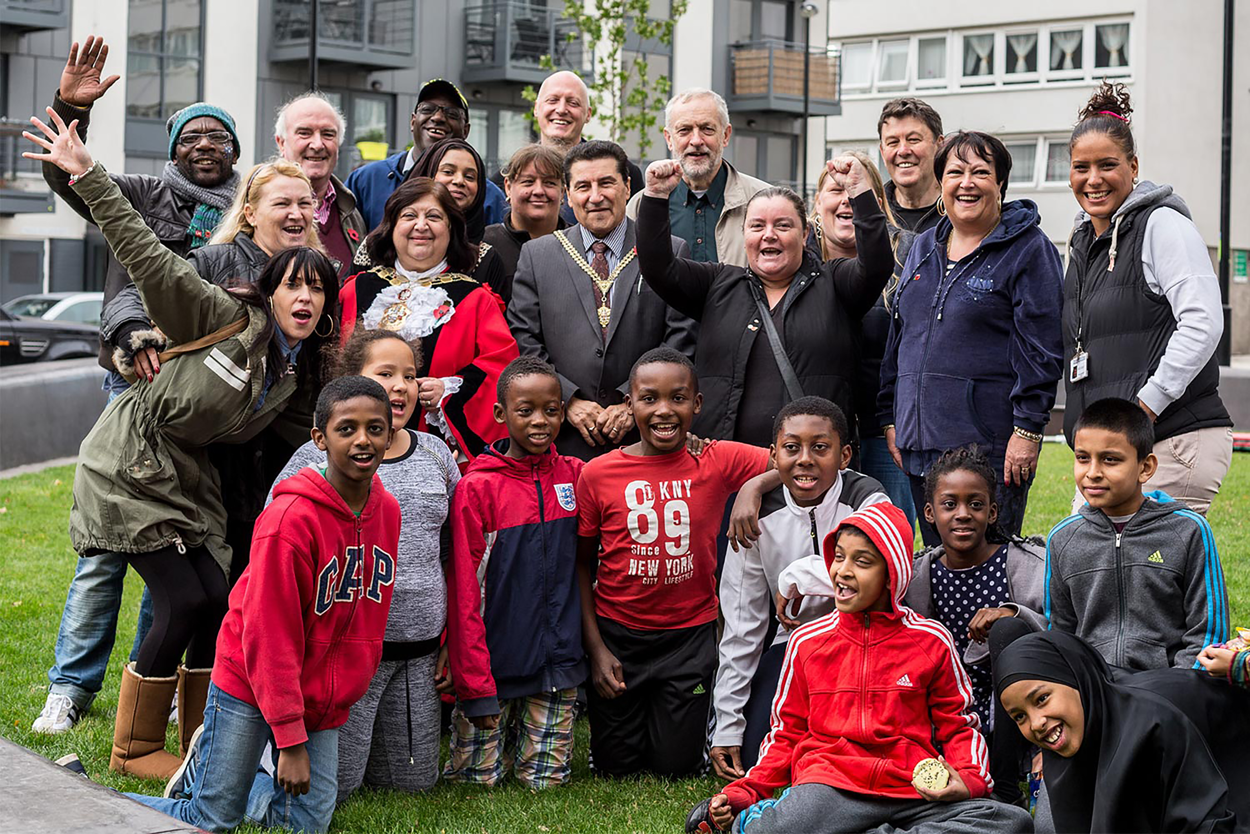 A crowd of adults and children from diverse backgrounds smiling and posing for a photograph.