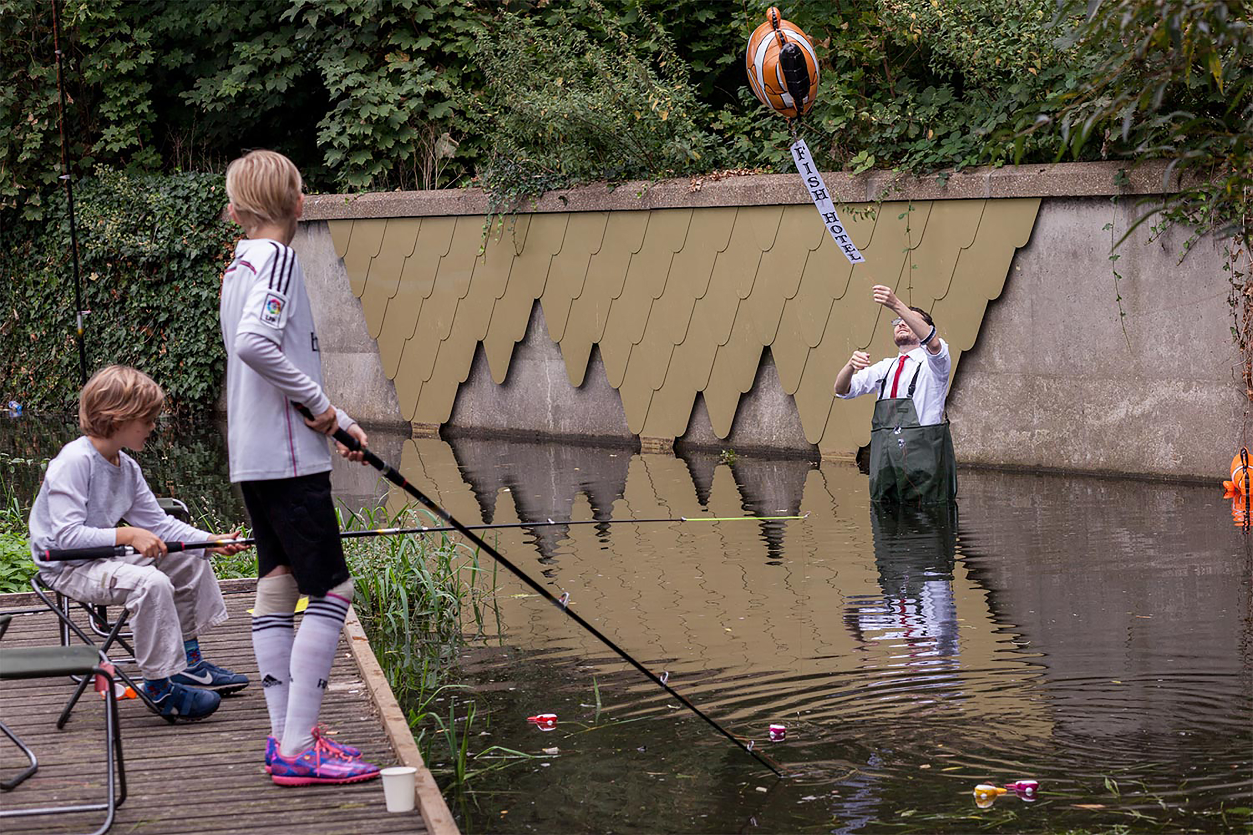 Two boys fishing in a shallow river with a man standing in the river releasing a clown fish helium balloon.