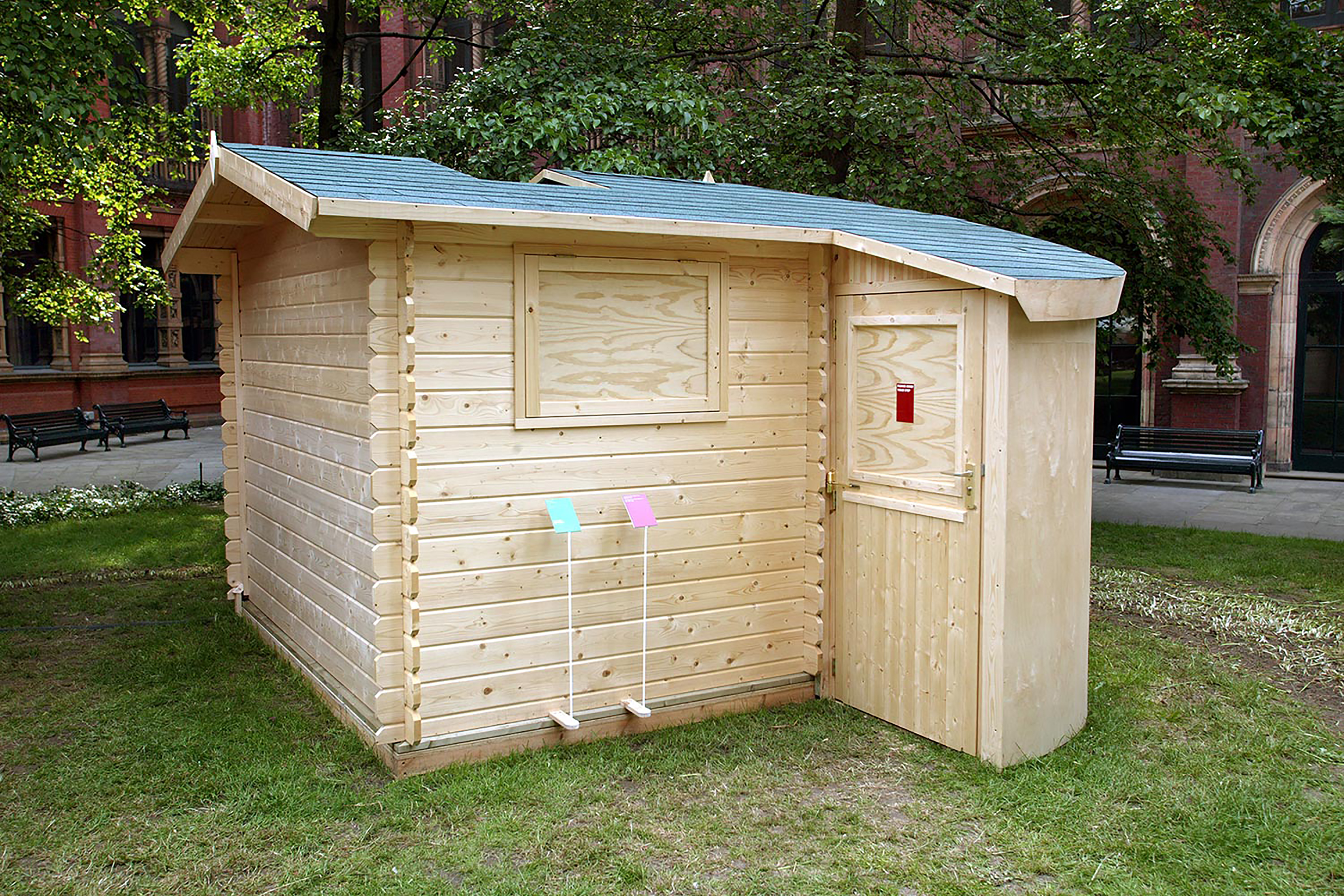 A brown wooden garden shed on a patch of grass behind.