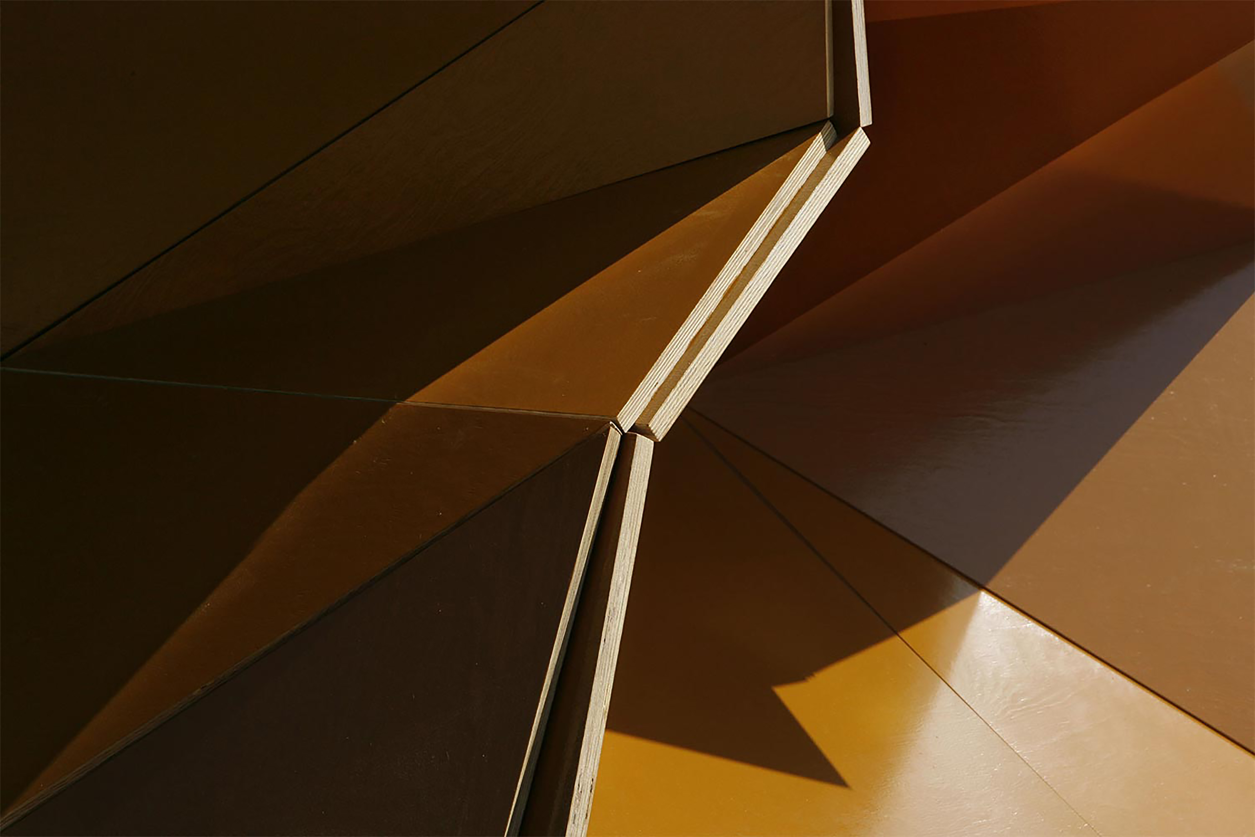 Close up of a brown sculpture with various geometric angles that are reflecting the light into different directions.