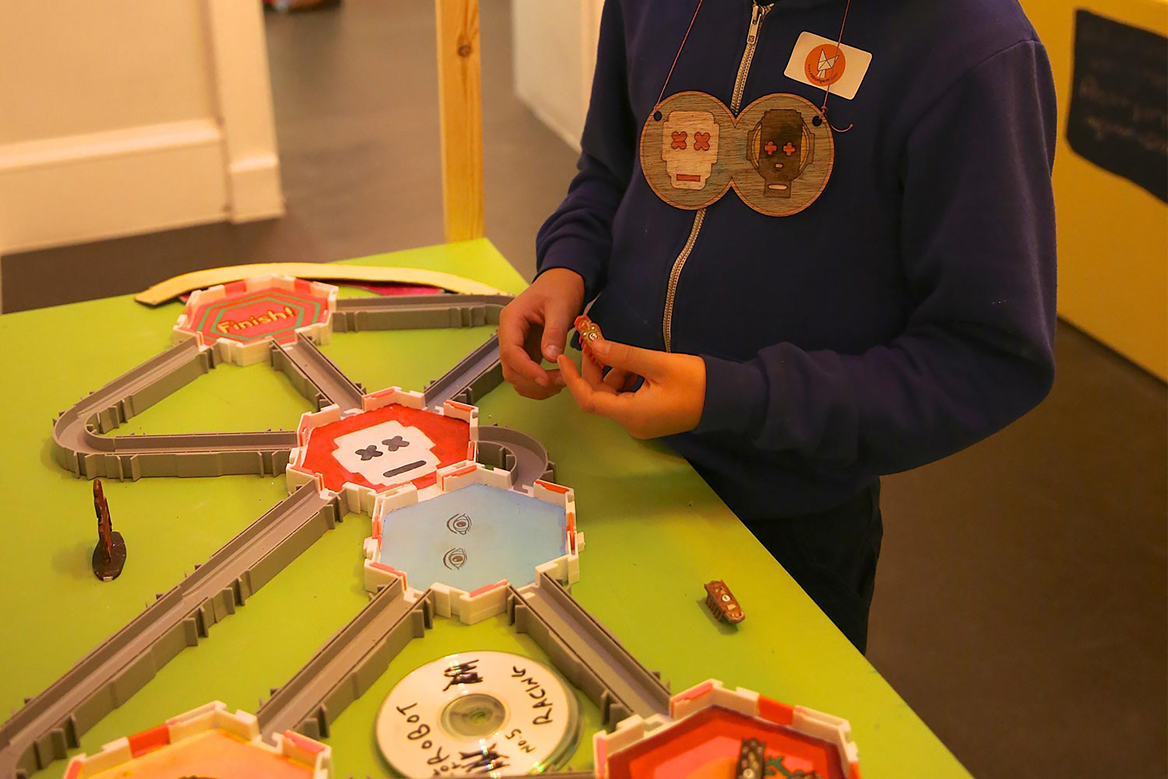 A child playing with figures across a miniature model road detailed with robot faces.