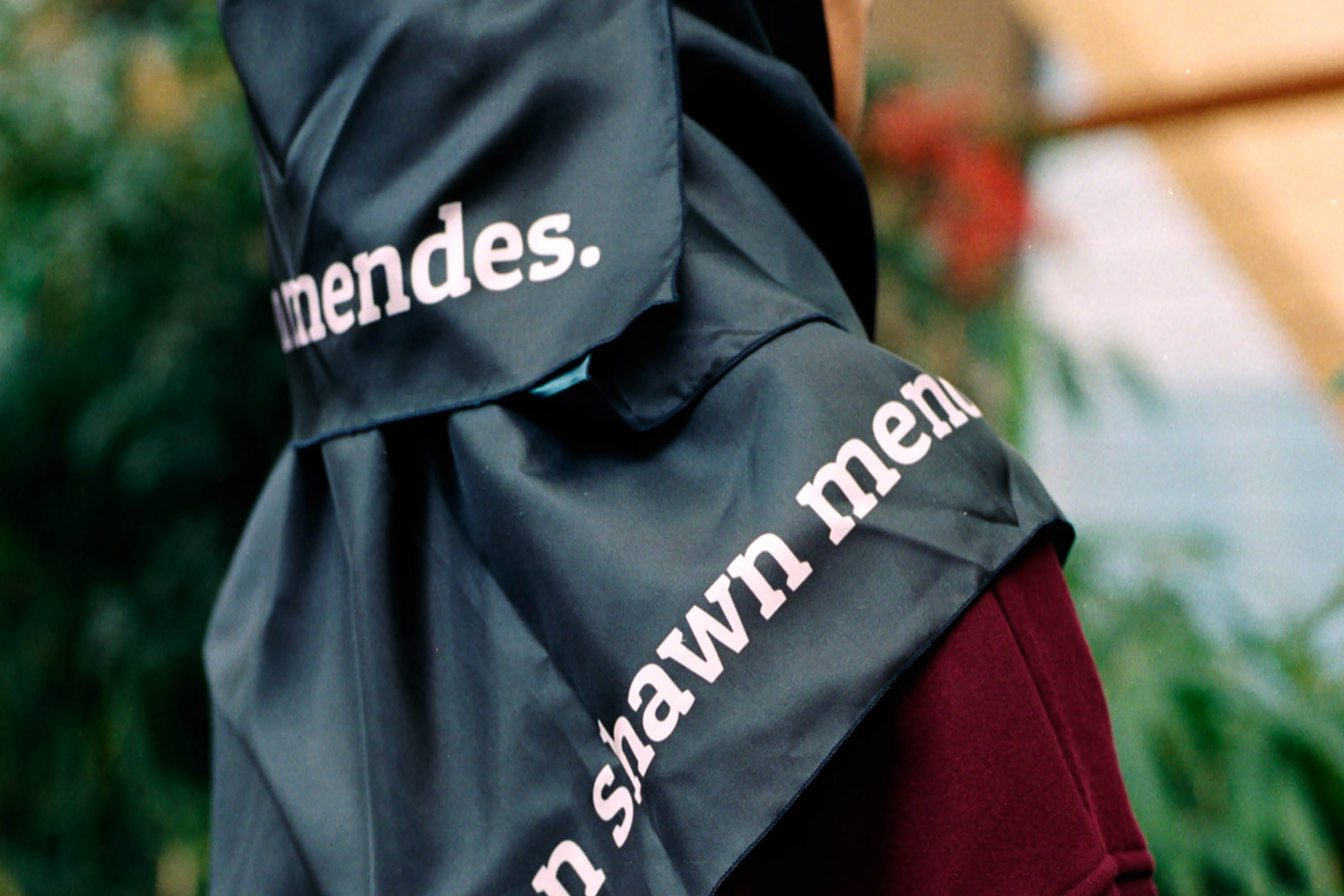 The back of a person’s head wearing a shiny black hijab with the words “Shawn Mendes”.