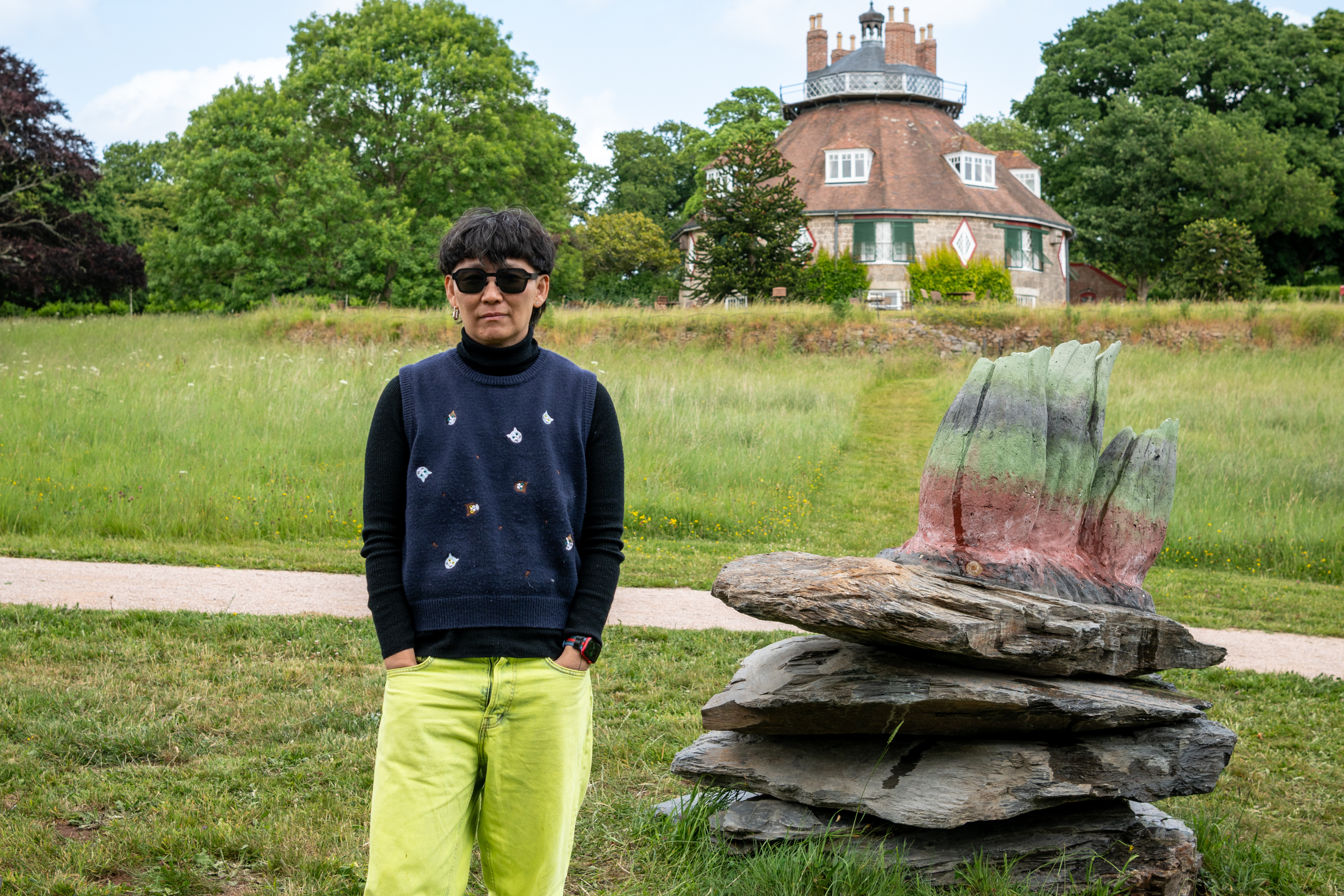Anne Duk Hee Jordan stood next to the barnacle sculpture in front of A la Ronde.