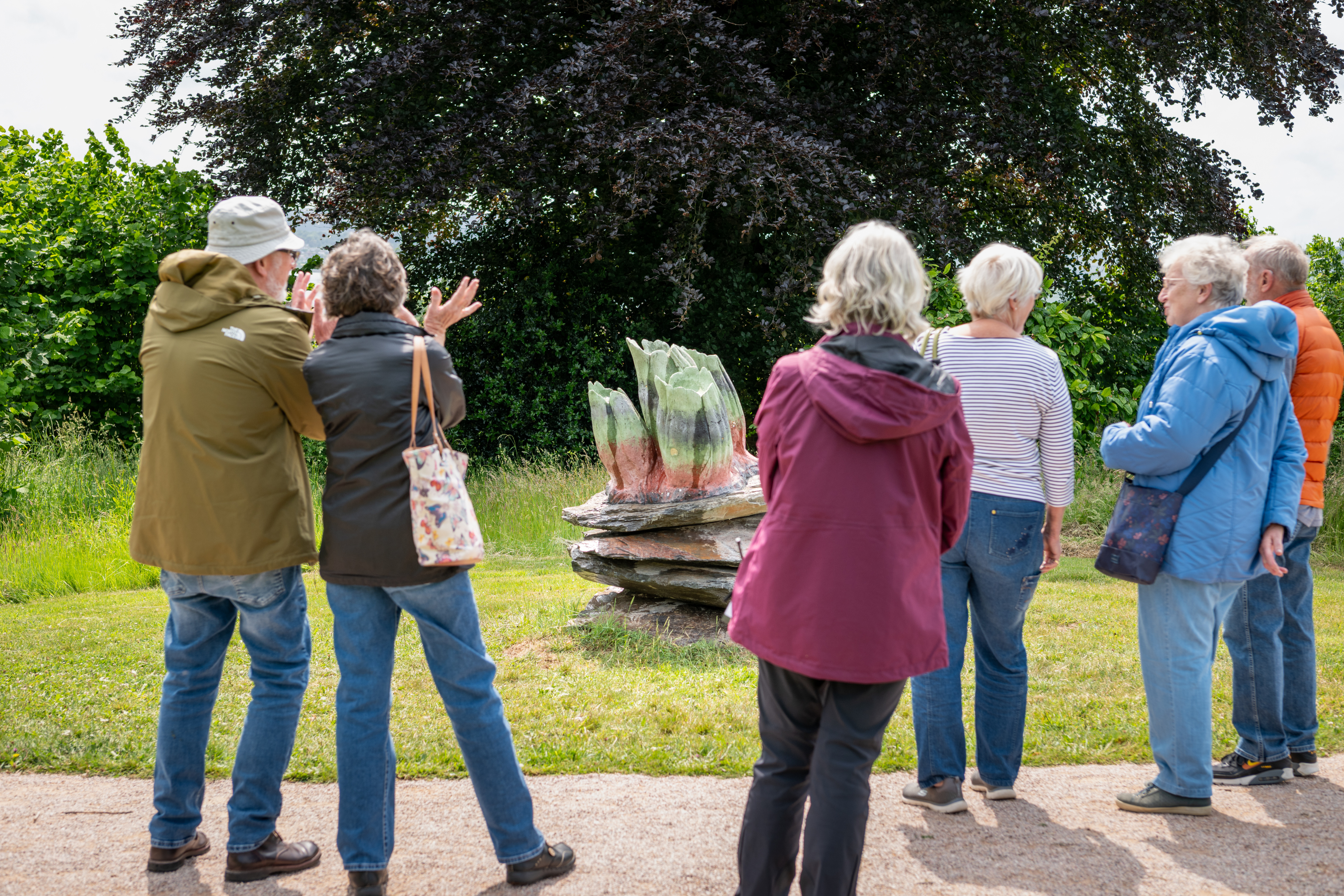 A group of people crowded round and looking at a sculpture of barnacle forms